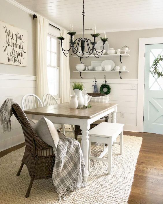 a traditional farmhouse dining nook with open shelves, a wooden table, wooden and wicker chairs and a metal chandelier