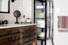 a vintage farmhouse bathroom with a vintage wooden vanity, a metal and glass armoire for storage and mirrors