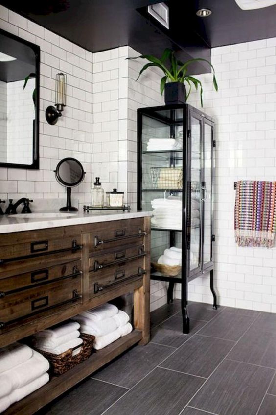 a vintage farmhouse bathroom with a vintage wooden vanity, a metal and glass armoire for storage and mirrors