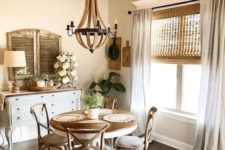 a vintage farmhouse dining area with wicker shades, a vintage wooden dining set, a white sideboard, shutters and a wooden chandelier