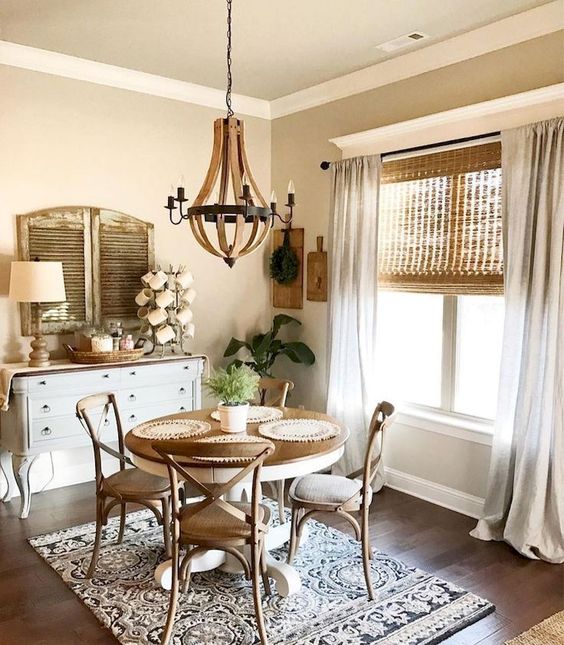 a vintage farmhouse dining area with wicker shades, a vintage wooden dining set, a white sideboard, shutters and a wooden chandelier