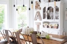 a vintage farmhouse dining room with a white buffet, a wooden sign, a ladder with bulbs, a wooden table and metal chairs