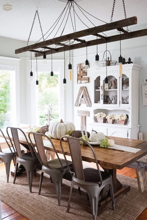 a vintage farmhouse dining room with a white buffet, a wooden sign, a ladder with bulbs, a wooden table and metal chairs