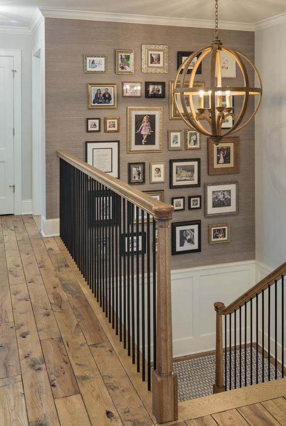 una pared de galería de inspiración vintage con fotos en marcos que no coinciden sobre la escalera es una idea de decoración acogedora