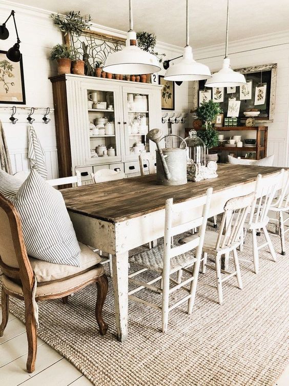 a welcoming farmhouse dining area with whitewashed furniture, upholstered chairs, white pendant lamps and a neutral buffet