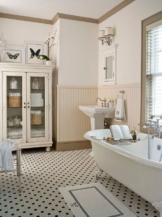 a welcoming neutral bathroom with penny tiles on the floor, sady beadboard, a clawfoot tub and a glass armoire for storage a welcoming neutral bathroom with penny tiles on the floor, sady beadboard, a clawfoot tub and a glass armoire for storage