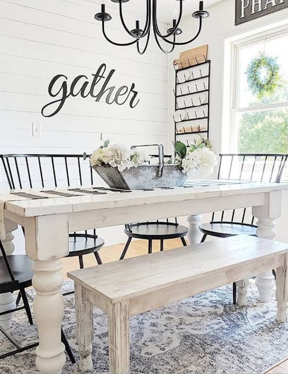 an airy and welcoming farmhouse dining room with a white dining set, black chairs, a black chandelier and much light