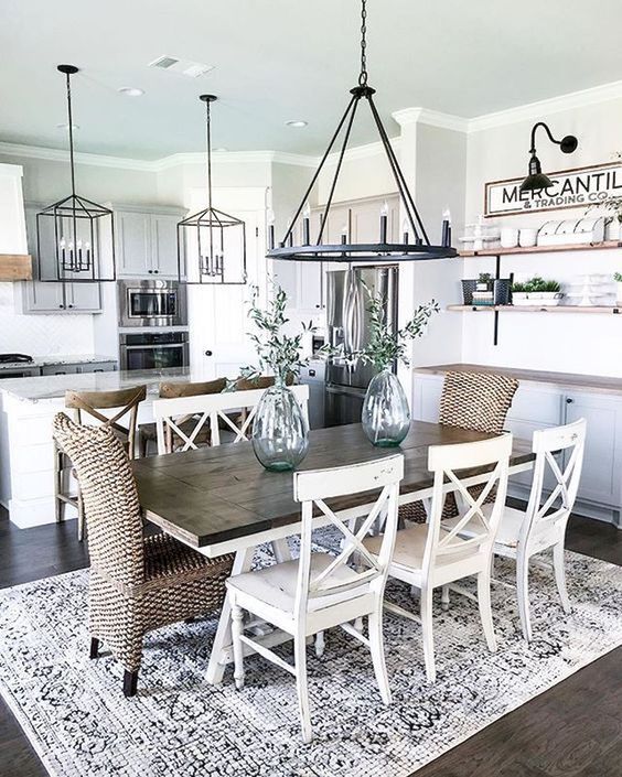 an airy modern farmhouse dining area with a wooden table, wicker and wooden chairs and open shelving