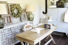 an inspiring home office with white beadboard walls, a wooden desk, a shabby chic storage unit, a black lamp and some decor