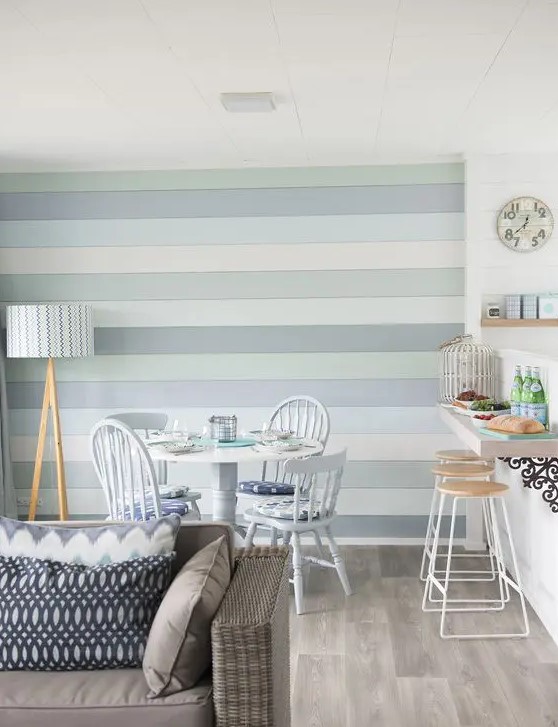 a beach space with a small breakfast bar, a dining space and a living room and a coastal-colored accent wall for a statement