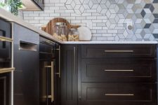 a stylish kitchen with black cabinets and a geometric backsplash