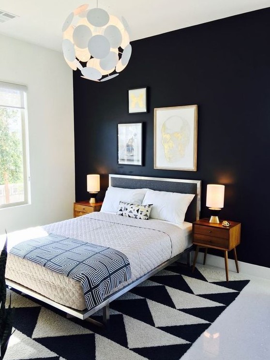 a bold and dramatic mid-century modern bedroom with a black statement wall, a geometric rug, a black bed and rich-stained nightstands