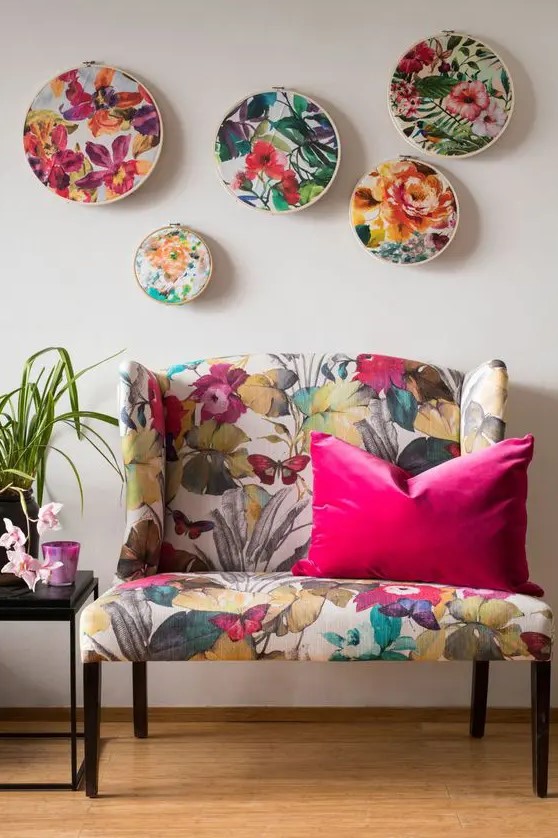 a bold floral loveseat, a gallery wlal with floral embroidery are cool and bright additions to a living room