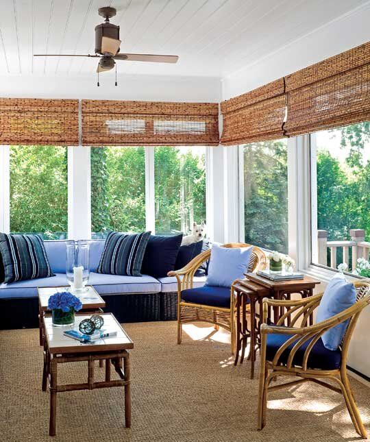 a bright beach sunroom with a rattan furniture, bright blue and navy upholstery and bamboo tables and shades