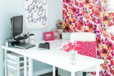a bright home office with a bold floral accent wall, a white corner desk and a chair with a bright pillow, an artwork