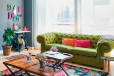 a bright living room with a console table and a colorful frame gallery wall, a green sofa, a bright floral rug and coffee tables
