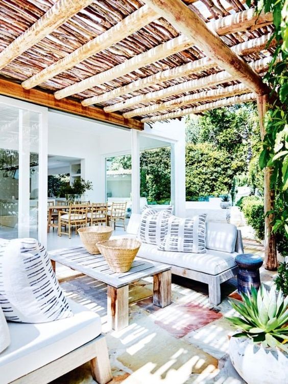 a bright summer terrace with wooden furniture, watercolor rugs and striped pillows feels very island-like