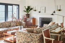 a catchy living room with a fireplace, floral sofas, a coffee table and a console table, black lamps and a chandelier