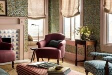 a catchy vintage living room with green floral wallpaper, a green sofa, burgundy chairs and a blue one, a plaid ottoman and a printed rug