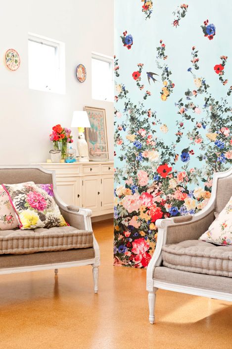 a catchy vintage space with a blue floral accet wall, taupe furniture and floral pillows and some vintage decor