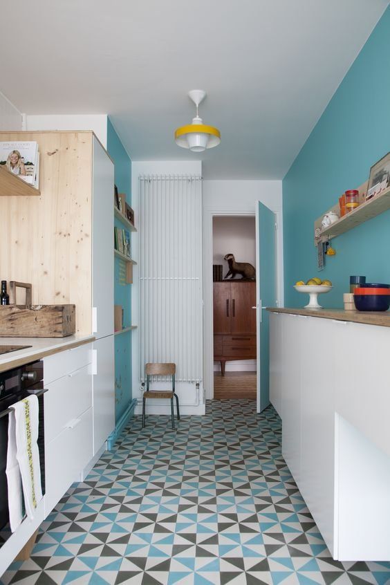a chic kitchen with sleek white cabients and turquoise walls, a bright geometric tile floor, open shelves is a cool space