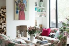 a chic living room with a non-working fireplace, floral sofas, a bench as a coffee table, a crystal chandelier