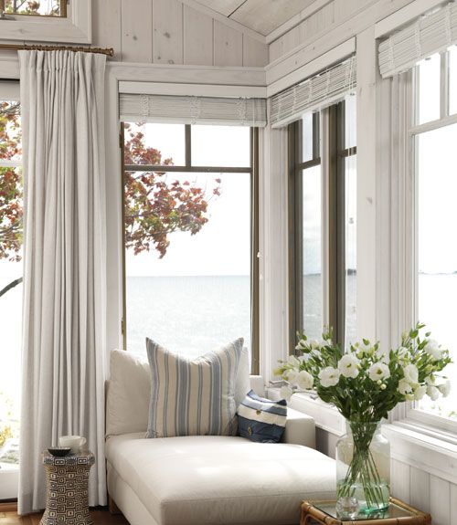 a coastal sunroom with a modern neutral daybed, striped pillows and neutral textiles plus gorgeous sea views a coastal sunroom with a modern neutral daybed, striped pillows and neutral textiles plus gorgeous sea views