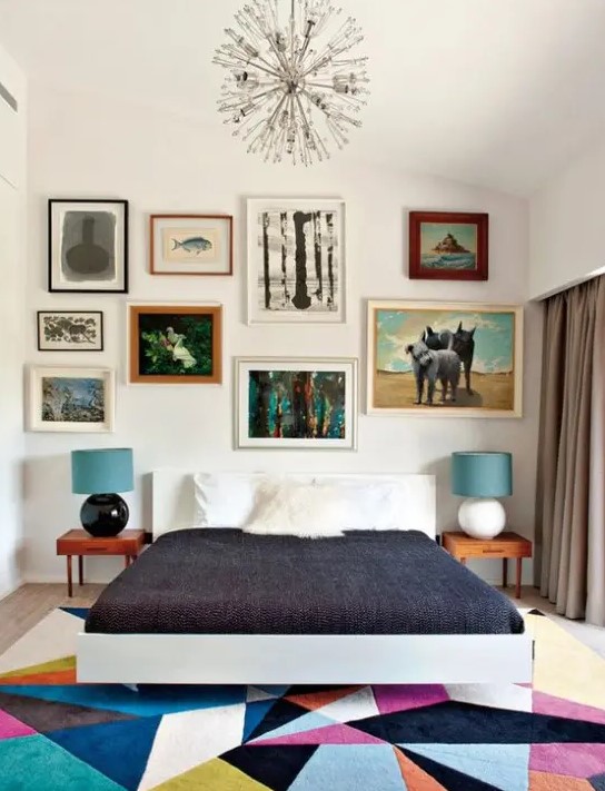 a colorful mid century modern bedroom with a bright geometric rug, a bed, laconic nightstands and an eclectic gallery wall