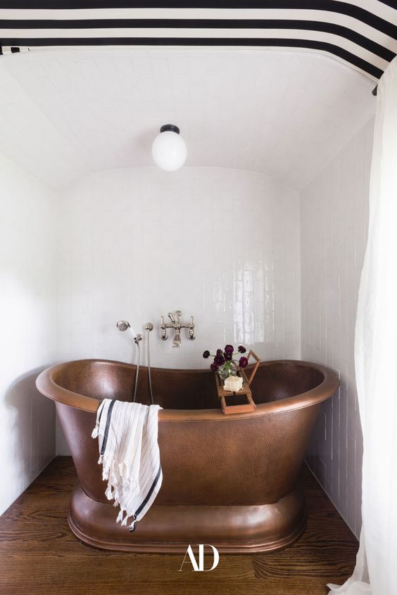 a copper bathtub in the niche with a striped black and white ceiling over it is amazing and it looks very chic