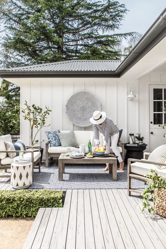 a cozy Scandinavian terrace with simple wooden furniture, white upholstery, a lemon tree and striped pillows