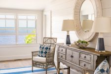 a fab seaside entryway with a shabby chic console table, a round mirror, bamboo chairs and a striped rug for adding color
