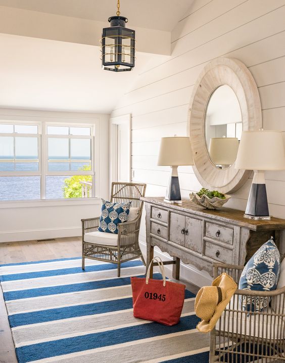 a fab seaside entryway with a shabby chic console table, a round mirror, bamboo chairs and a striped rug for adding color