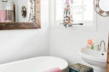 a farmhouse bathroom with a hex tile floor, a black bathtub, a mirror in a stained frame, a bold floral curtain and stool