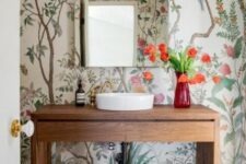 a farmhouse bathroom with bright wallpaper, a stained vanity, bold blooms and a square mirror is elegant