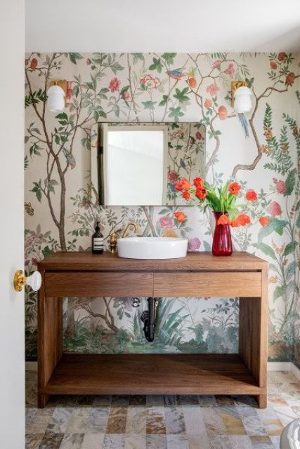 a farmhouse bathroom with bright wallpaper, a stained vanity, bold blooms and a square mirror is elegant