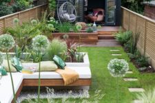 a fresh and welcoming summer terrace with a deck, a built-in bench, a lawn and some greenery and other plants