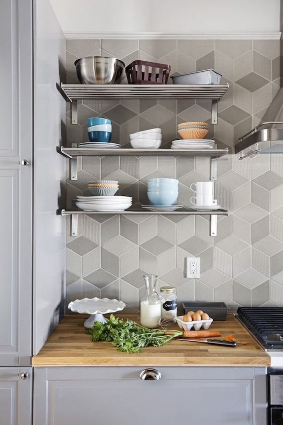 a grey kitchen with shaker style cabinets, open metal shelves, a grey geo tile backsplash, butcherblock countertops