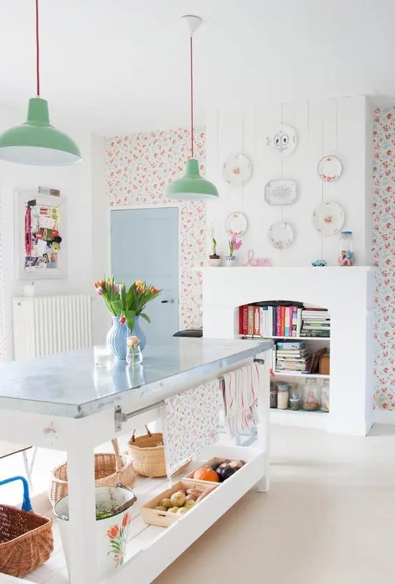 a kitchen with bright floral wallpaper, a non working fireplace with book storage, a kitchen island and green pendant lamps