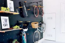 a light-filled entryway with a black pegboard wall with lots of shelves, hangers, hooks and with bike holders is a gorgeous idea for a contemporary space