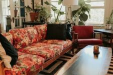 a mid-century modern lviing room with a black and white rug, a floral sofa, rust-colored chairs, potted plants and a floor lamp