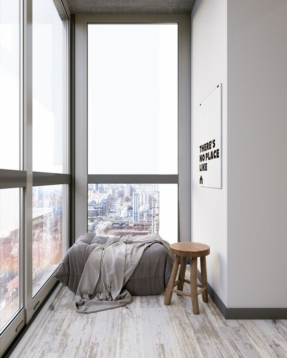 a minimalist sunroom with a comfy daybed, a blanket and a stool is all you need to relax