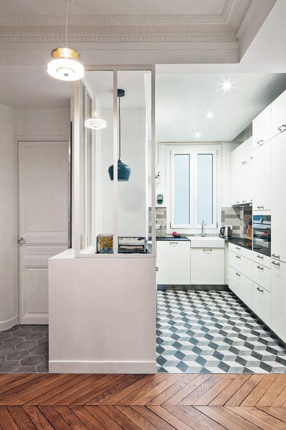 a modern white kitchen with black handles, a black and white geometric tile floor, a black pendant lamp and black countertops