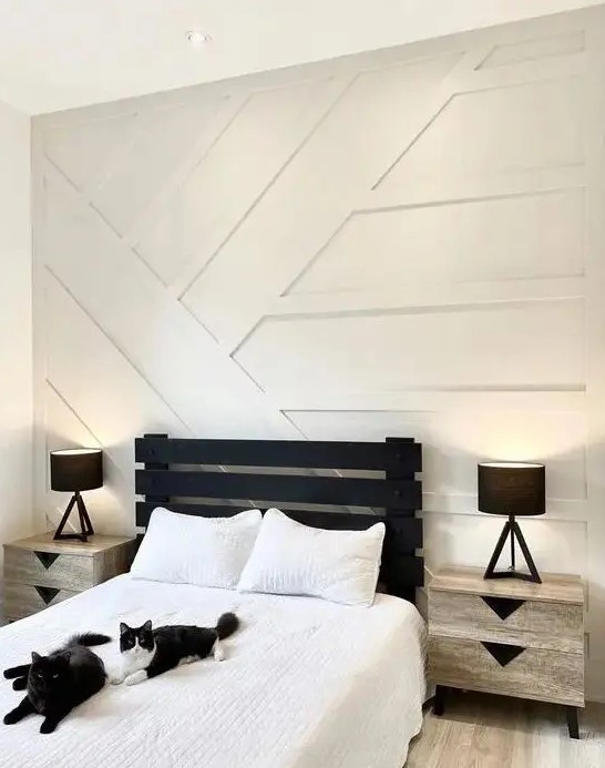 a monochromatic guest bedroom with a white paneled wall, a black bed and neutral nightstands is a chic and bold idea