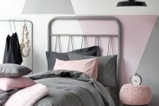 a pretty Scandinavian bedroom with an accent geo wall in muted colors, a grey bed, a makeshift closet and a black pendant lamp