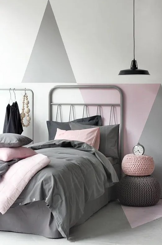 a pretty Scandinavian bedroom with an accent geo wall in muted colors, a grey bed, a makeshift closet and a black pendant lamp
