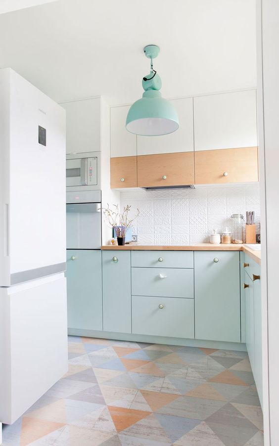 a pretty pastel Scandinavian kitchen with mint cabinetry, a white and stained cabinets, with a pastel geo print floor and a mint pendant lamp