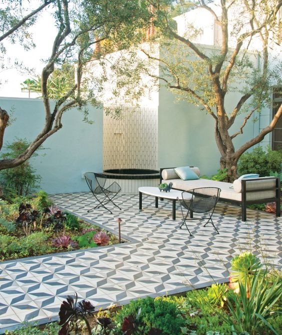 a refined modern terrace with a Mediterranean feel with greenery and succulents, a tiled deck, metal furniture and a fountain