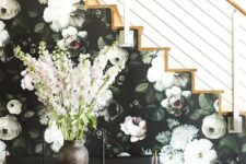 a side of the stairs covered with moody floral wallpaper in dark greens and neutrals
