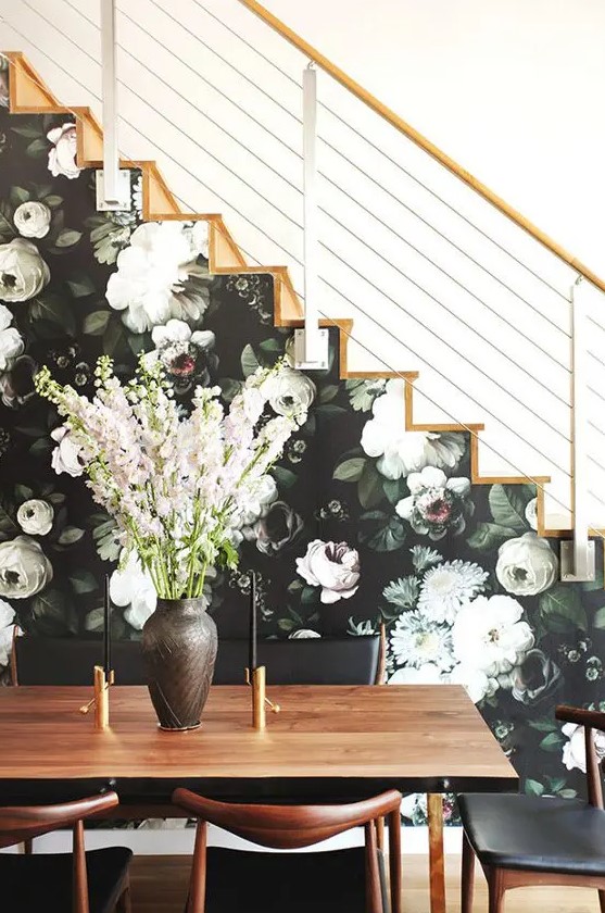 a side of the stairs covered with moody floral wallpaper in dark greens and neutrals