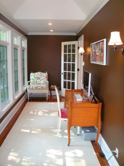 a small colorful sunroom turned into a home office, with vintage inspired furniture and prints